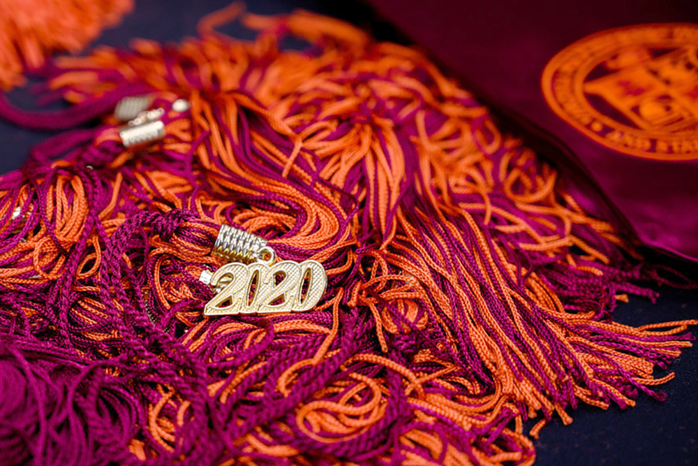 Maroon and orange graduation tassels piled in a messy heap with 2020 in the center.