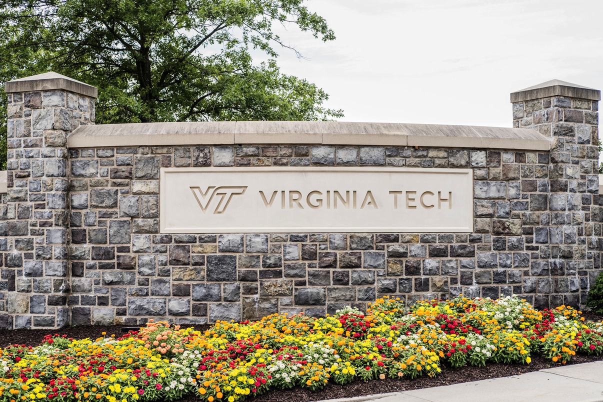 Stone Virginia Tech sign with flowers in the foreground.