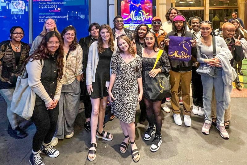 Teens pose for a group photo in the lobby of a theater.