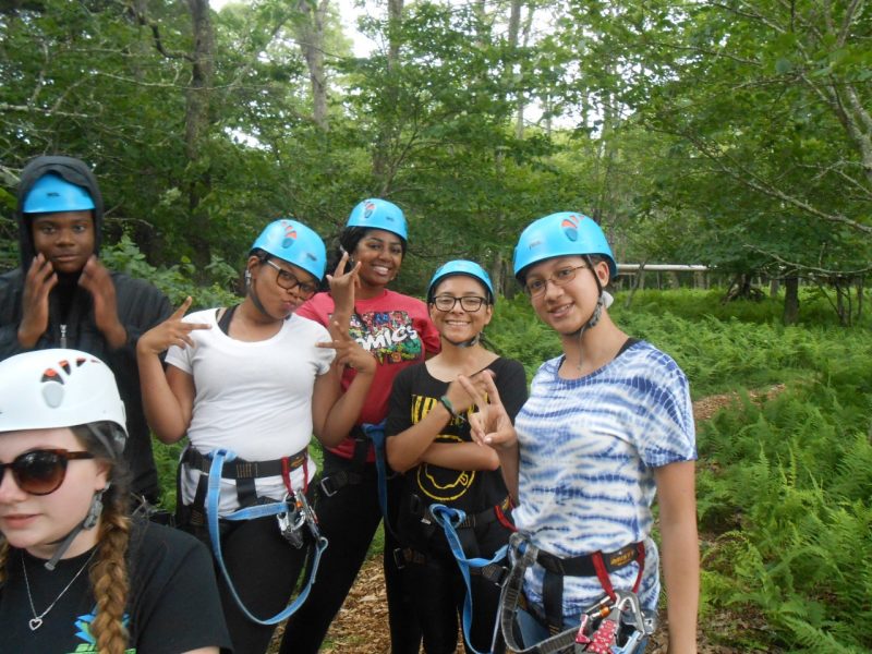Teens pose for a photo wearing blue helmets and harnesses.